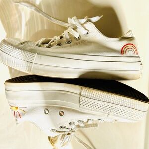 Ivory Converse sneakers with vibrant sun & rainbow side embroidery.
